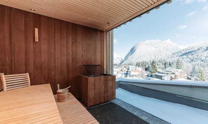 Modern wooden sauna with panoramic view of snowy alpine village and mountains